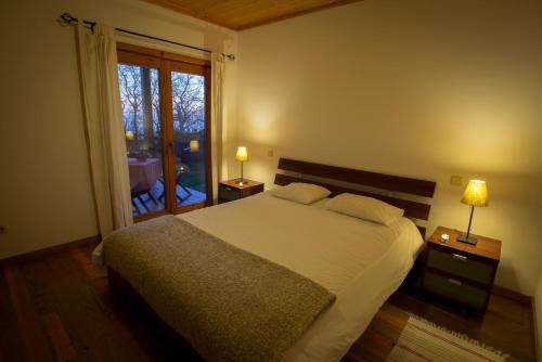 a bedroom with a bed with two lamps and a window at Quinta dos Curubas in Vila Franca do Campo