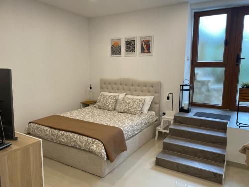 a bedroom with a bed and a window and stairs at GlamByAJ with free parking and Netflix in Pula