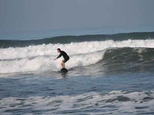 un hombre montando una ola en una tabla de surf en el océano en Ayolah surf House & Medewi Surf Camp, en Jembrana