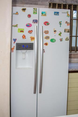 - un réfrigérateur blanc avec des aimants dans la cuisine dans l'établissement House of ours Dreams, à Abomey-Calavi
