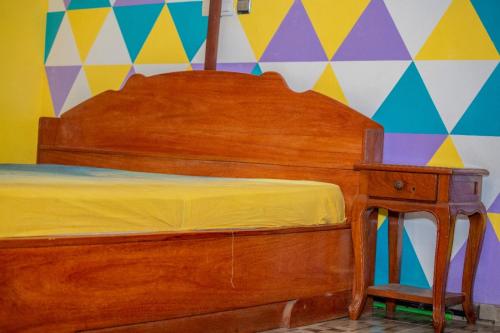 - un lit en bois avec une commode en bois et un mur coloré dans l'établissement House of ours Dreams, à Abomey-Calavi