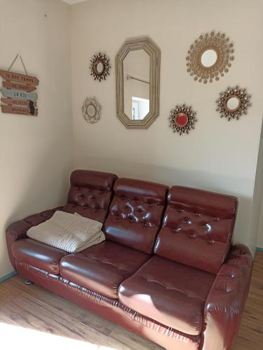 a brown leather couch in a living room with mirrors at La Bruyère - B & B - in Tréban