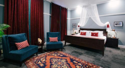 a bedroom with a bed and two chairs at Grand Pacific Hotel in Suva
