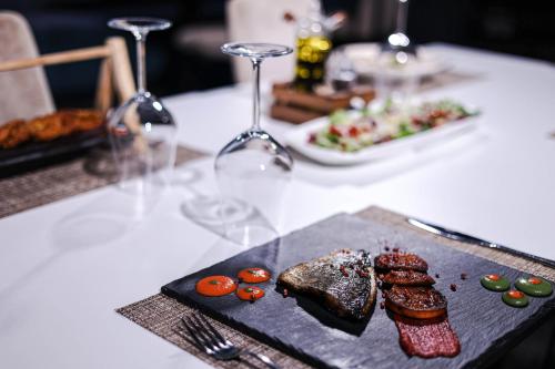 a plate of food on a table with wine glasses at Hotel Frojd - Beach Front Resort in Shëngjin