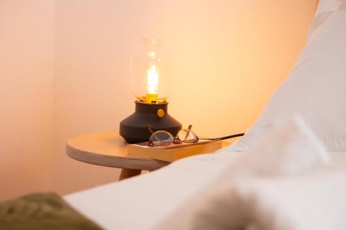 a lamp on a table next to a bed at Modern Central Seaview Apartment Saranda in Sarandë