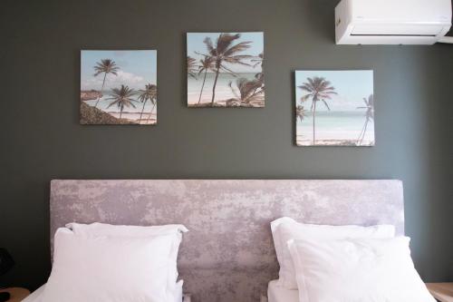 three pictures of palm trees on a wall above a bed at Modern Central Seaview Apartment Saranda in Sarandë