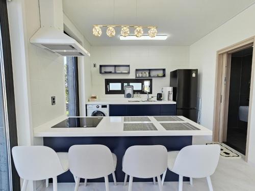 a kitchen with a counter with four white chairs at Check-in Jeju Private Full Stay in Jeju