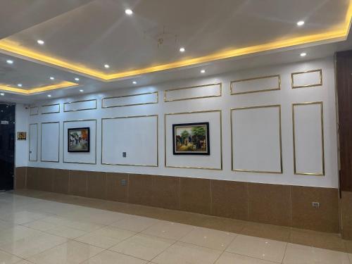 HOÀNG GIA Hotel ĐÔNG ANH في Dong Anh: غرفة بجدران بيضاء وصور على الحائط