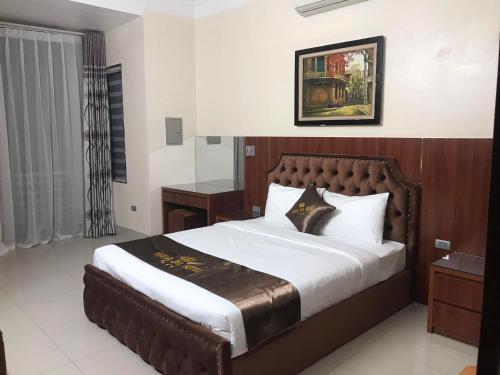 HOÀNG GIA Hotel ĐÔNG ANH في Dong Anh: غرفة نوم بسرير كبير مع اللوح الخشبي