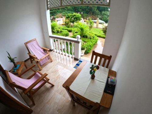 a dining room with a table and chairs and a large window at La Residence D'Almee Guesthouse in Anse Possession