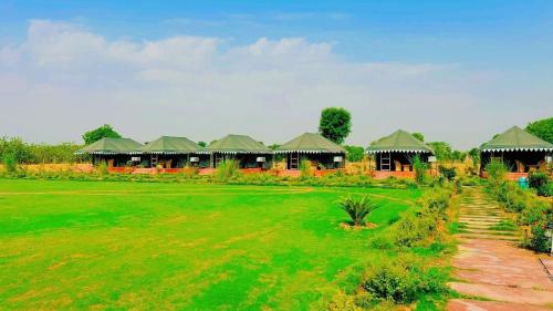 a resort with a green field and some buildings at Pritampalace resort in Khilchipur