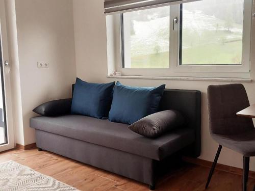 a couch with blue pillows in a room with a window at Beautiful and Cosy Flat in Wagrain in Wagrain