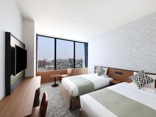 a hotel room with two beds and a flat screen tv at HOTEL MYSTAYS Kumamoto Riverside in Kumamoto