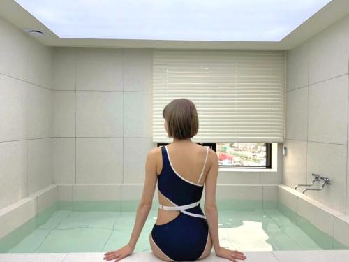 a woman sitting in a tub in a bathroom at Hound Hotel Gijang Osiria in Busan