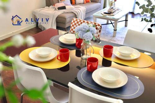 a dining room table with yellow plates and red cups at Costa Mahkota - 1min I Mahkota Parade Mall I Dataran Pahlawan I Mahkota Hospital in Melaka
