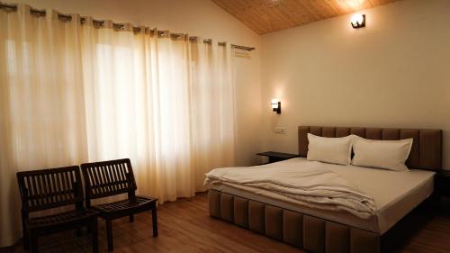 sypialnia z łóżkiem, krzesłem i oknem w obiekcie Saanjh Cottages w mieście Bir