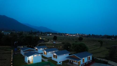 a row of houses in a field at night w obiekcie Saanjh Cottages w mieście Bir