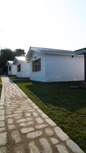 a white building with a grass yard next to a road at Saanjh Cottages in Bīr