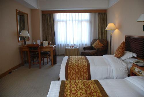 a hotel room with two beds and a desk at Qingdao Oceanwide Elite Hotel in Qingdao