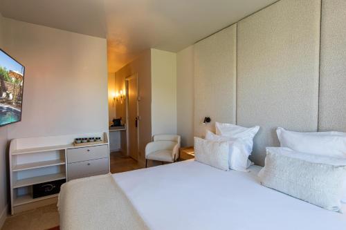 a hotel room with a white bed and a desk at Lou Cagnard in Saint-Tropez