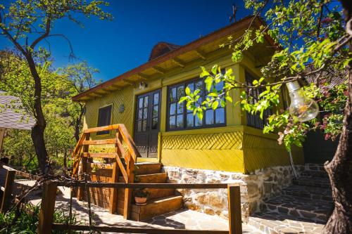 Une petite maison jaune avec des escaliers en face de celle-ci dans l'établissement Alunis Retreat, à Aluniş