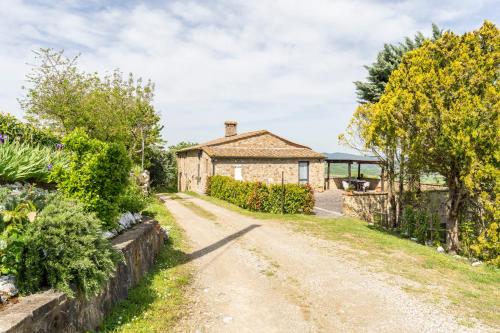 an old stone house with a garden and a dirt road at Podere Marcigliana in Radicondoli