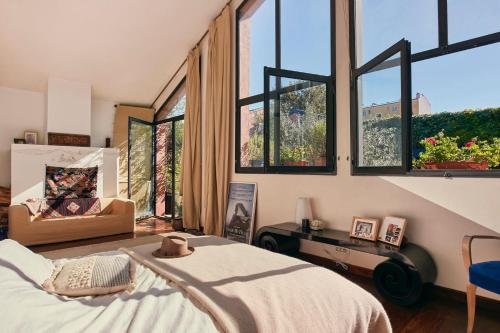 - une chambre avec de grandes fenêtres, un lit et une chaise dans l'établissement Enchanted Candy Factory Retreat, à Montreuil