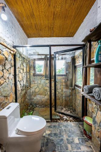 a bathroom with a toilet and a stone wall at Lim's house in Mai Châu