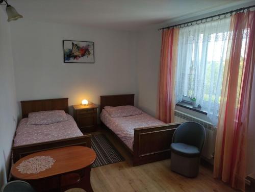 a bedroom with two beds and a table and a chair at Pod Modrzewiem ul Modrzewiowa 7 in Milicz