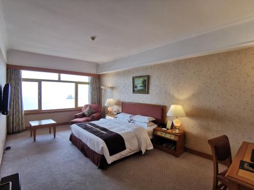 um quarto de hotel com uma cama e um sofá em Qingdao Oceanwide Elite Hotel em Qingdao