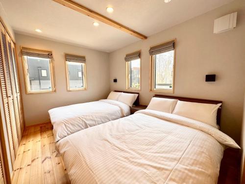 Duas camas num pequeno quarto com janelas em THE LIVIDA 軽井沢west コナラテラス em Karuizawa