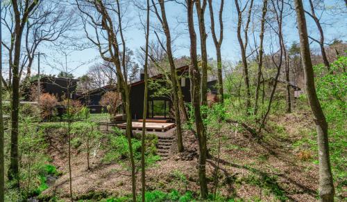 a house in the woods with a staircase leading up to it at THE LIVIDA 軽井沢west コナラテラス in Karuizawa