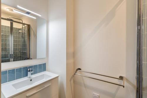 La salle de bains est pourvue d'un lavabo et d'un miroir. dans l'établissement Résidence MALO'INN - au cœur de Saint Malo, à Saint-Malo