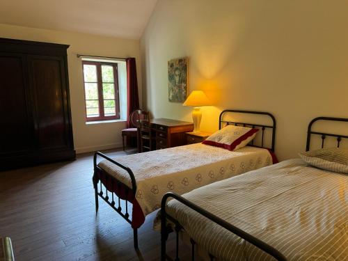 1 Schlafzimmer mit 2 Betten, einem Schreibtisch und einem Fenster in der Unterkunft La Maison des Poètes 6 personnes à Treigny Perreuse in Perreuse