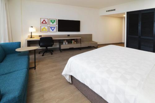 a hotel room with a bed and a desk and a tv at Holiday Inn Monterrey-Parque Fundidora by IHG in Monterrey