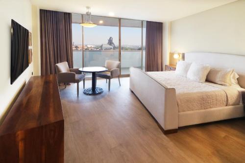 a hotel room with a bed and a table and chairs at Holiday Inn Monterrey-Parque Fundidora by IHG in Monterrey