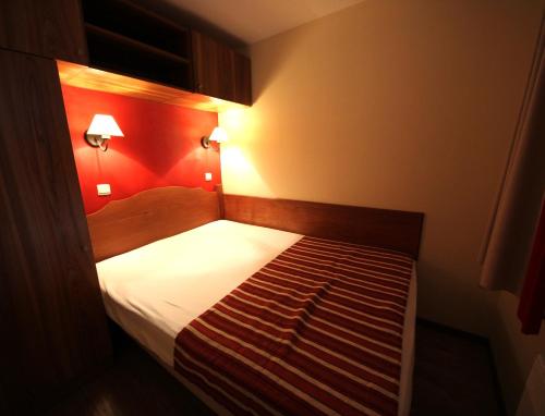 Cette petite chambre comprend un lit avec un mur rouge. dans l'établissement Au coeur de l'Ariège, à Ax-les-Thermes