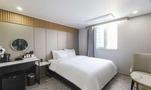 um quarto com uma grande cama branca e uma cadeira em JECHEON No 25 HOTEL em Jecheon