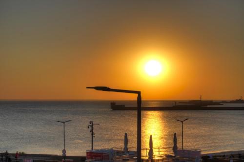 einen Sonnenuntergang über dem Meer mit Straßenbeleuchtung in der Unterkunft HelApart - z widokiem na morze in Hel