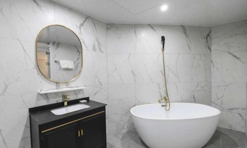 een badkamer met een bad, een wastafel en een spiegel bij JECHEON No 25 HOTEL in Jecheon