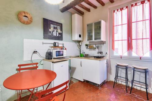une cuisine avec une table rouge, une table et des chaises dans l'établissement Charmant studio proche du Vieux Port, à Marseille