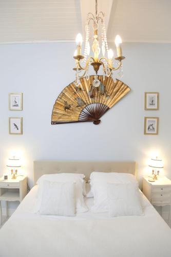 una camera da letto con un grande letto bianco e un lampadario a braccio di Le Refuge d'Alienor at Domaine Le Touran near Saint Emilion a Pellegrue