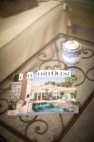 un magazine et un vase sur une table en verre dans l'établissement Le Refuge d'Alienor at Domaine Le Touran near Saint Emilion, à Pellegrue