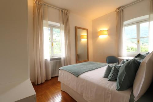 1 dormitorio con 1 cama con espejo y 2 ventanas en B&B Casa Ninni, en Camogli