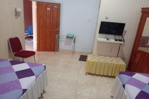 a room with two beds and a table and a television at Wisma Sederhana in Mamuju