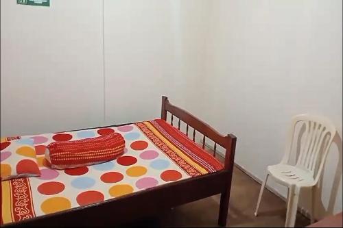 a bed with a polka dot blanket and a chair at Wisma Sederhana in Mamuju