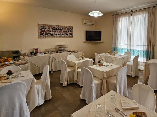 a banquet room with white tables and white chairs at Emerald Coast Hotel in Olbia