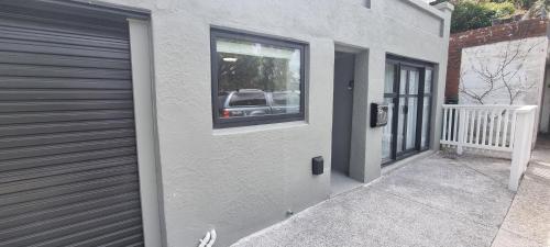 a building with a window with a car in the reflection at City Fringe Apartment with garage in Wellington
