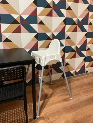 a white chair sitting next to a table in front of a wall at Cozy city center apartment in Visaginas