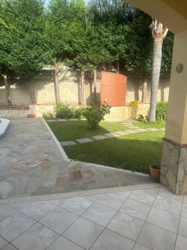 a patio with a yard with trees and grass at Villa Framaca in Furnari